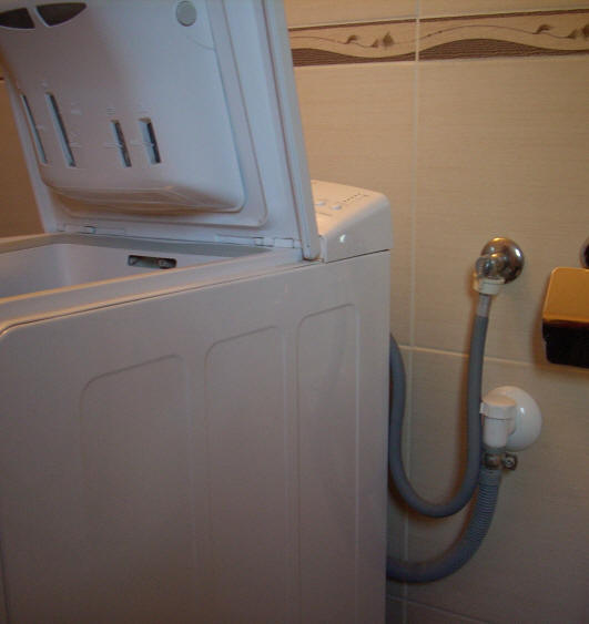 підключена автоматична пральна машинка до водопроводу і каналізації.